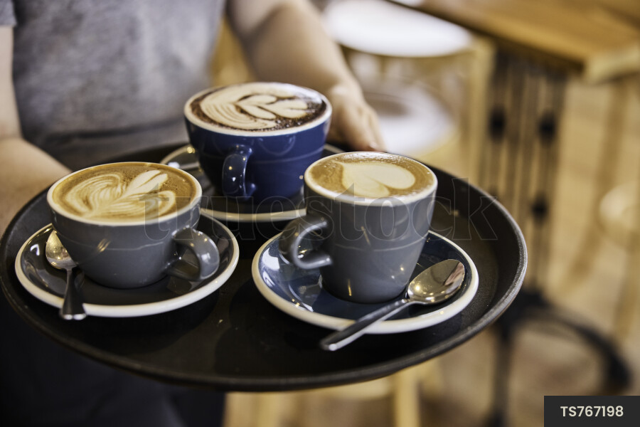 Close up of waitress carrying coffee in cafe