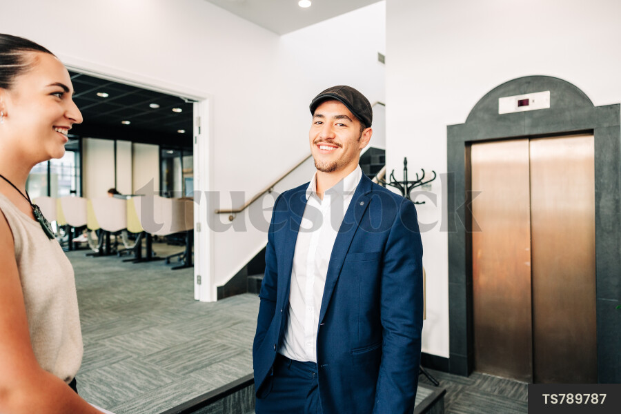 Young businesspeople smiling outside elevator in office building