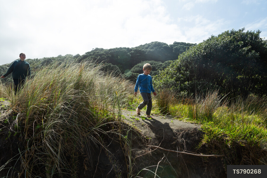 Boy and girl on sand dunes at PIha Beach