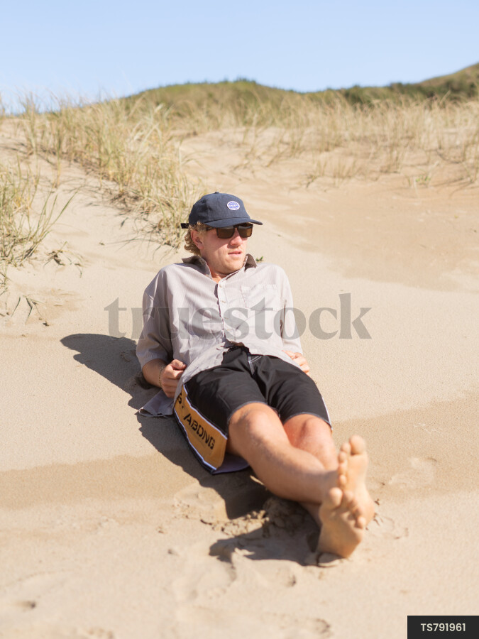 Young man lying on dunes at beach