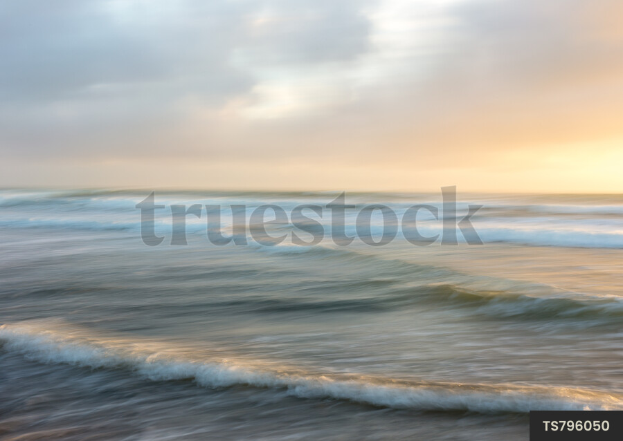 Waves on water under clouds during sunset