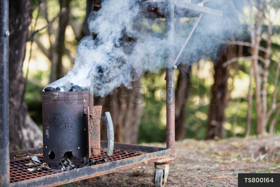 Smoke from coal burning in barbecue smoker in garden