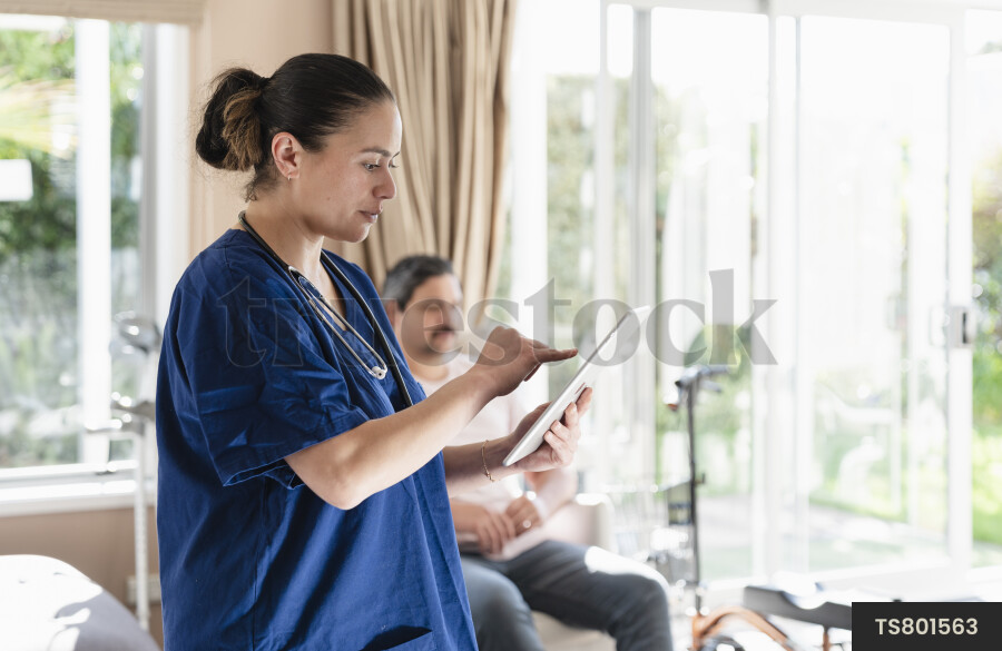 Patient with nurse using tablet pc in house