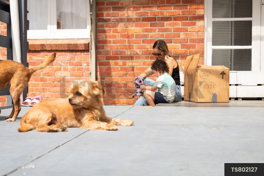Woman and daughter sitting on patio with dogs