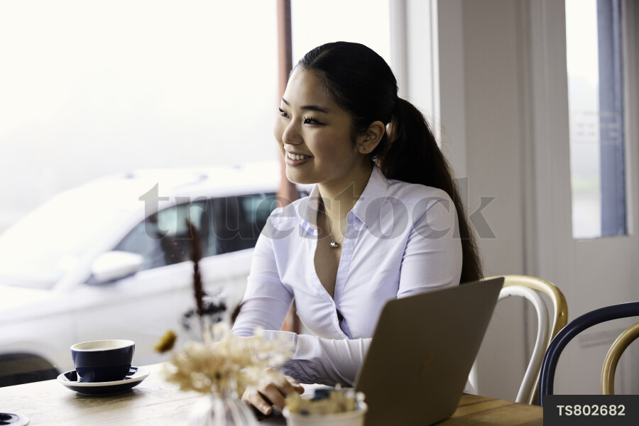 Woman working remotely with technology in cafe