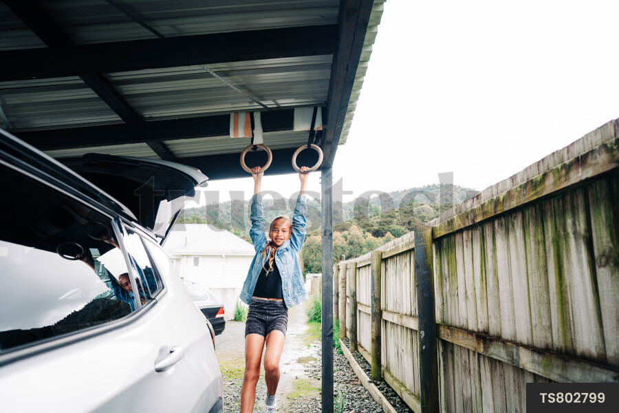 Girl playing with gymnastic rings under carport