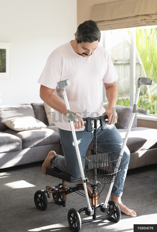 Disabled man with crutches in house