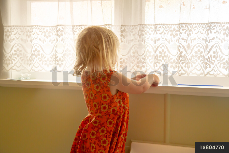 Girl by window with curtains