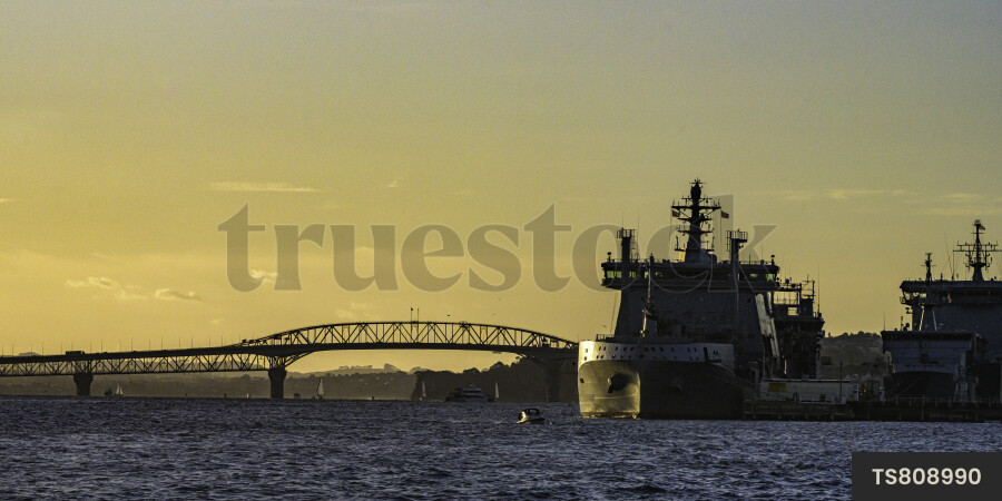 Navy ship and Auckland Harbour Bridge at sunset