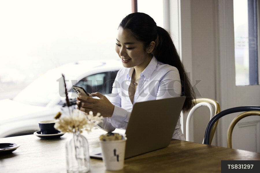 Woman working remotely with technology in cafe