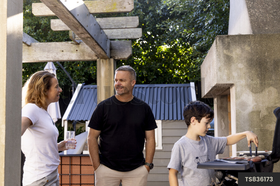 Family preparing food on barbecue grill in garden