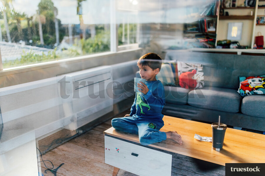 Young Boy Sitting on Table with Drink
