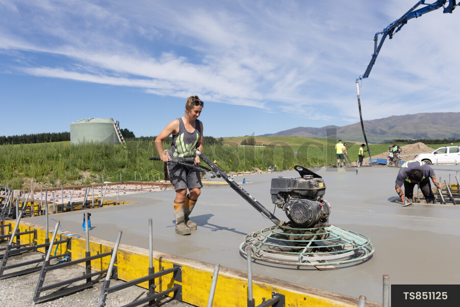 Construction workers pouring concrete on foundation