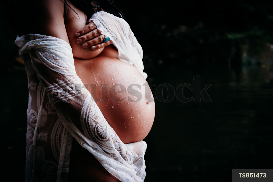 Pregnant woman holding stomach at night