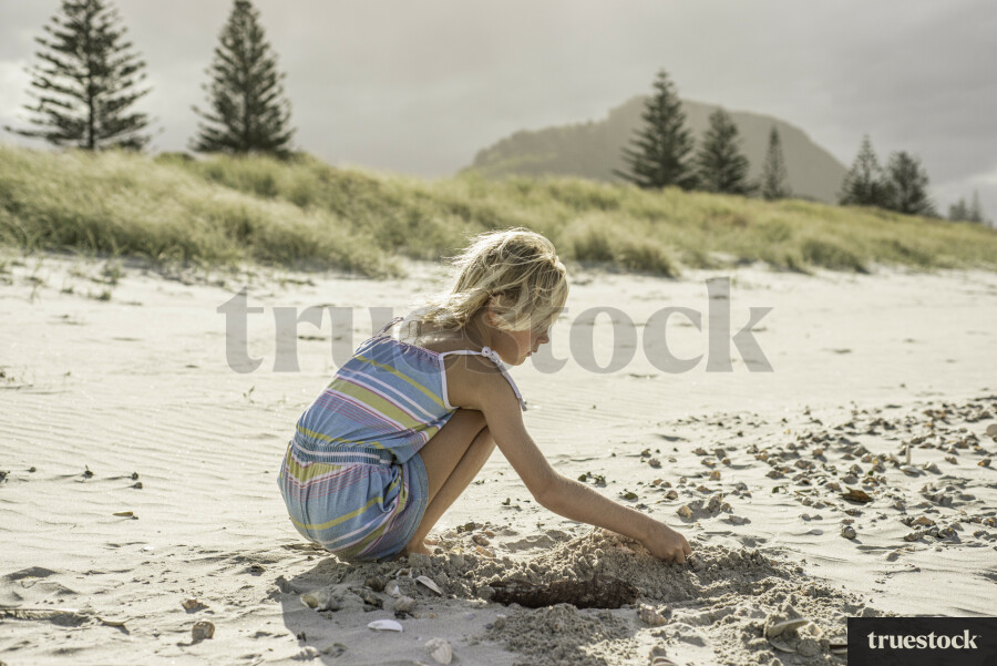 Young Girl Digging Hole in Sand