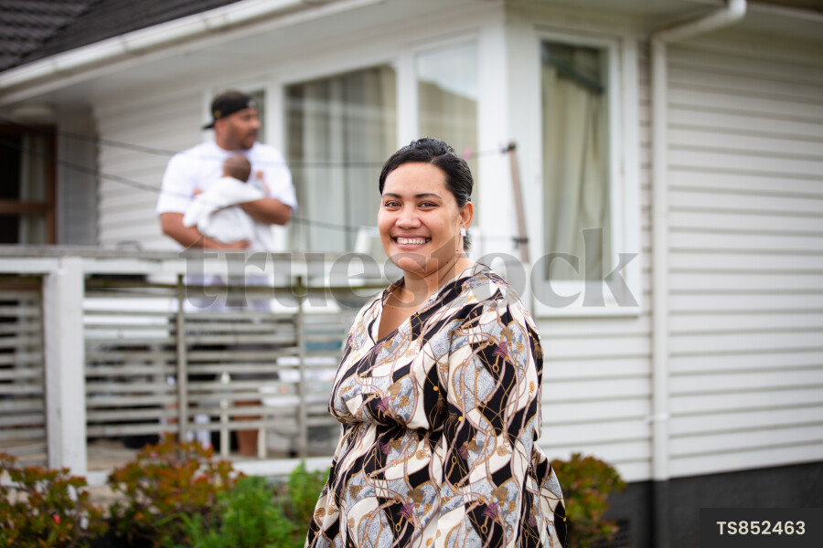 Happy tongan mother by family outside house