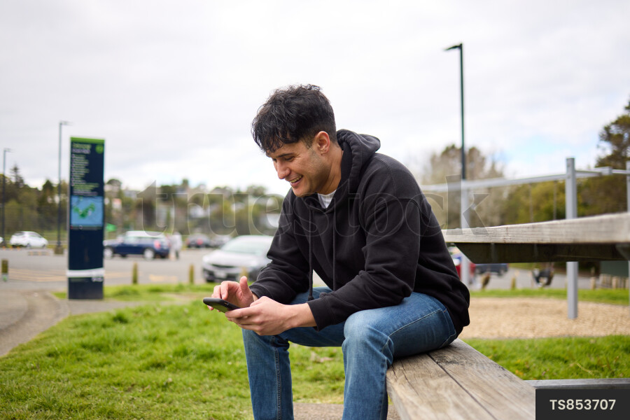 Man Using Phone on Park Bench
