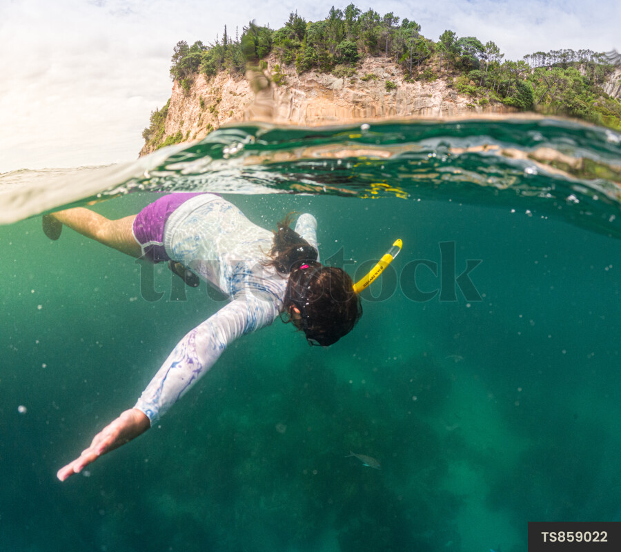 Girl scuba diving in sea by coastline
