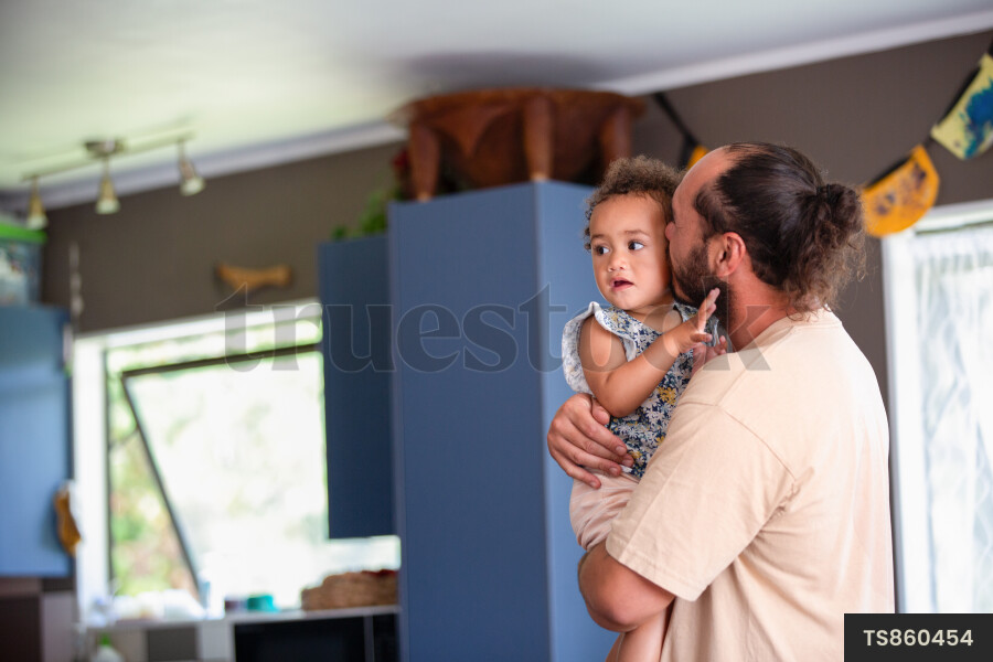 Maori dad kissing daughter on cheek in home