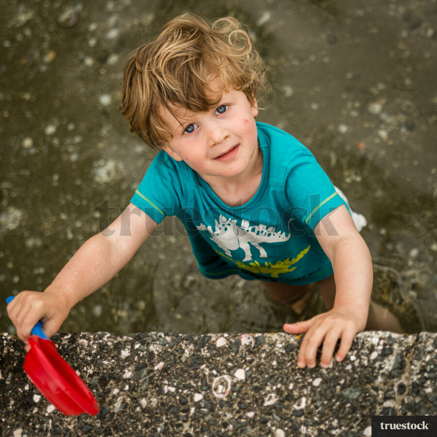 Child holding a toy shovel at the beach