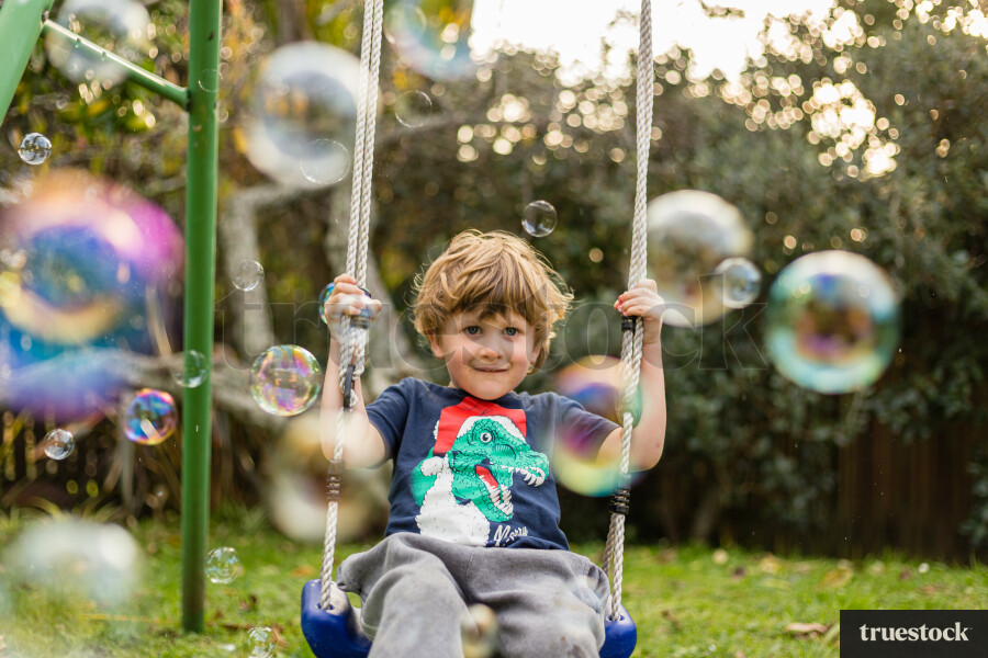 Child on the swing playing with bubbles