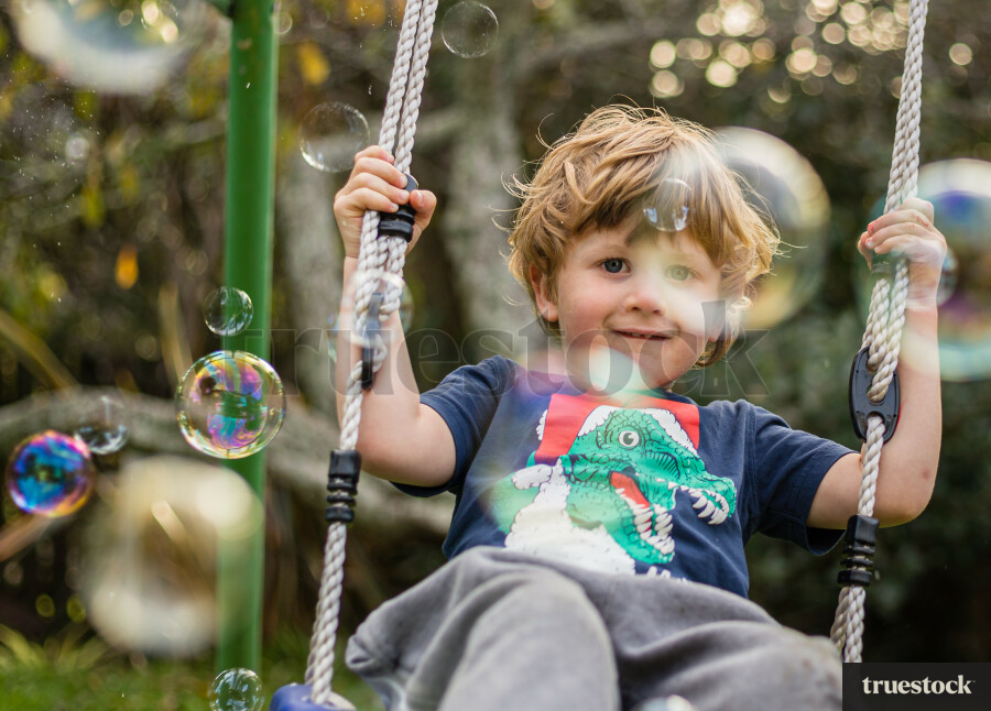 Child on the swing playing with bubbles