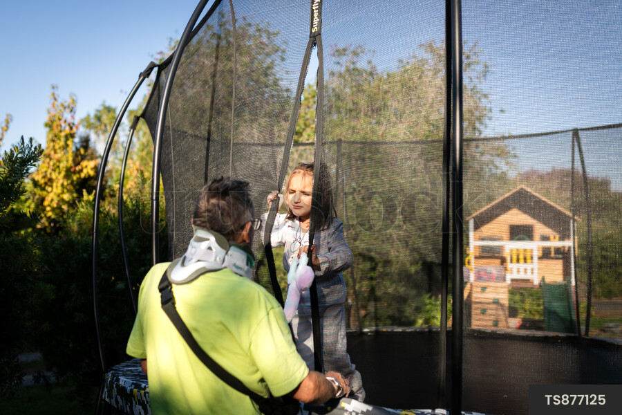 Girl playing on trampoline with her grandfather