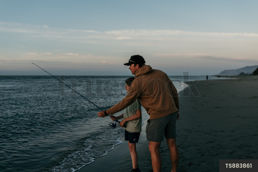 Man fishing with his son on beach