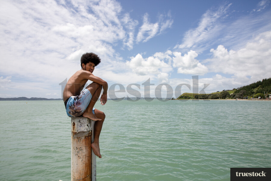 Teen Boy Sitting on Wharf Post