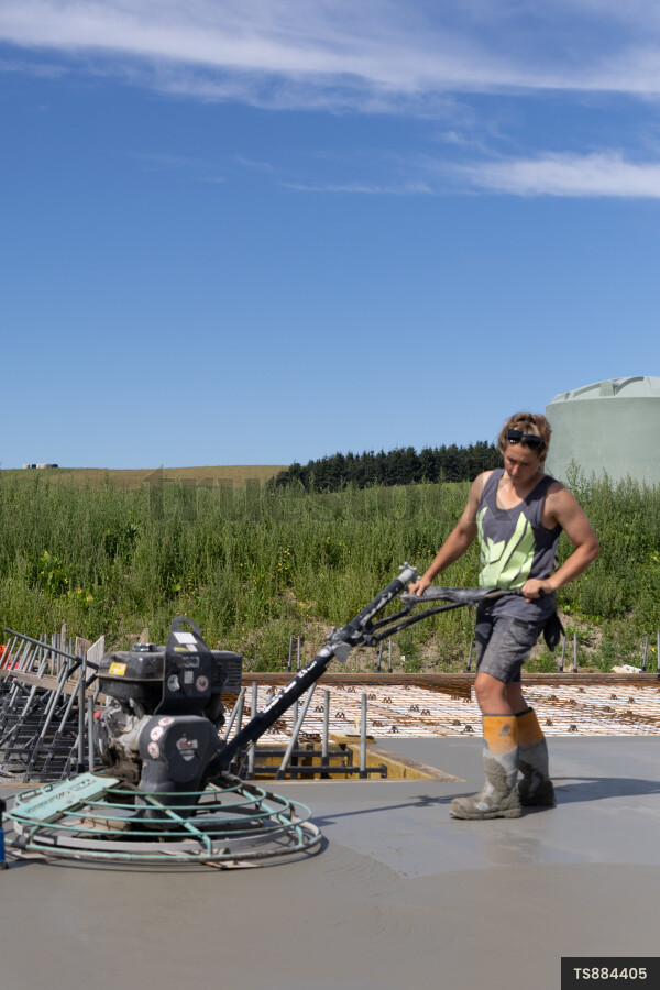 Female construction worker with machine on concrete