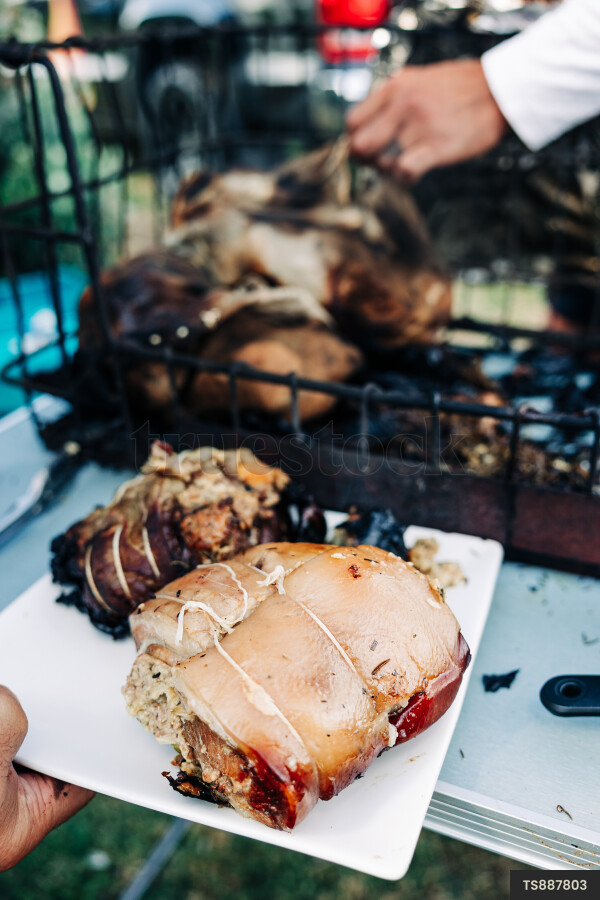Family with meat from hangi on table in back yard