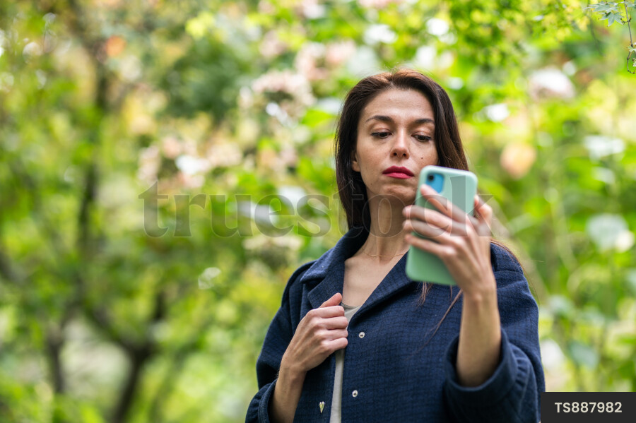 Young woman with smart phone in park
