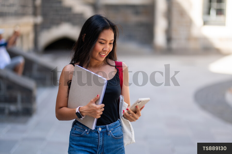 Smiling student with smartphone and book at university