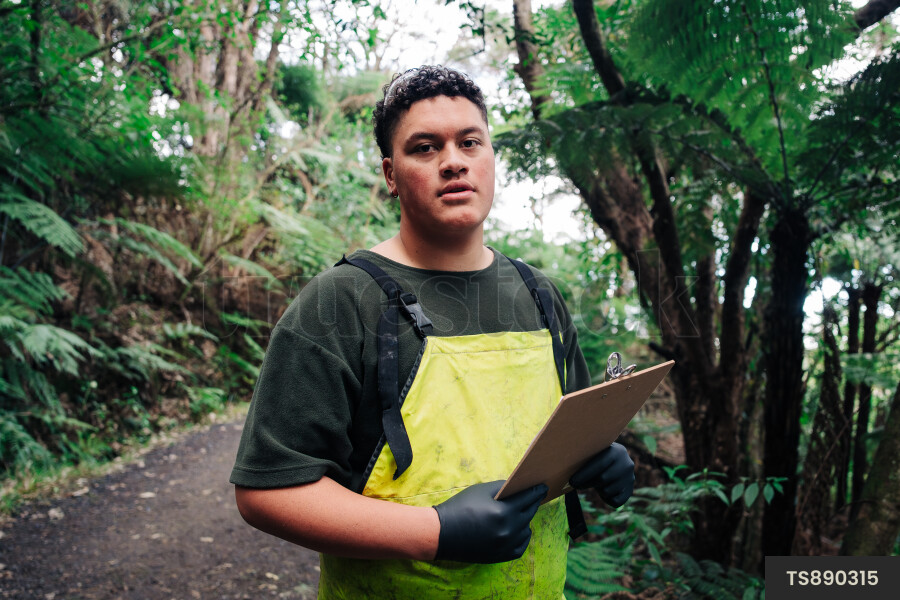 Young man holding clipboard in forest
