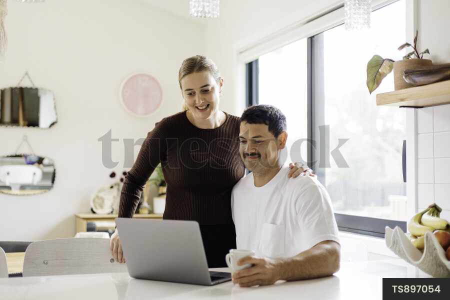 Couple Using Computer in Kitchen