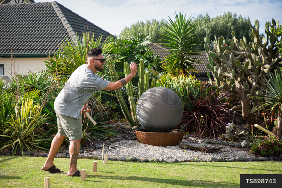 Man playing kubb on lawn