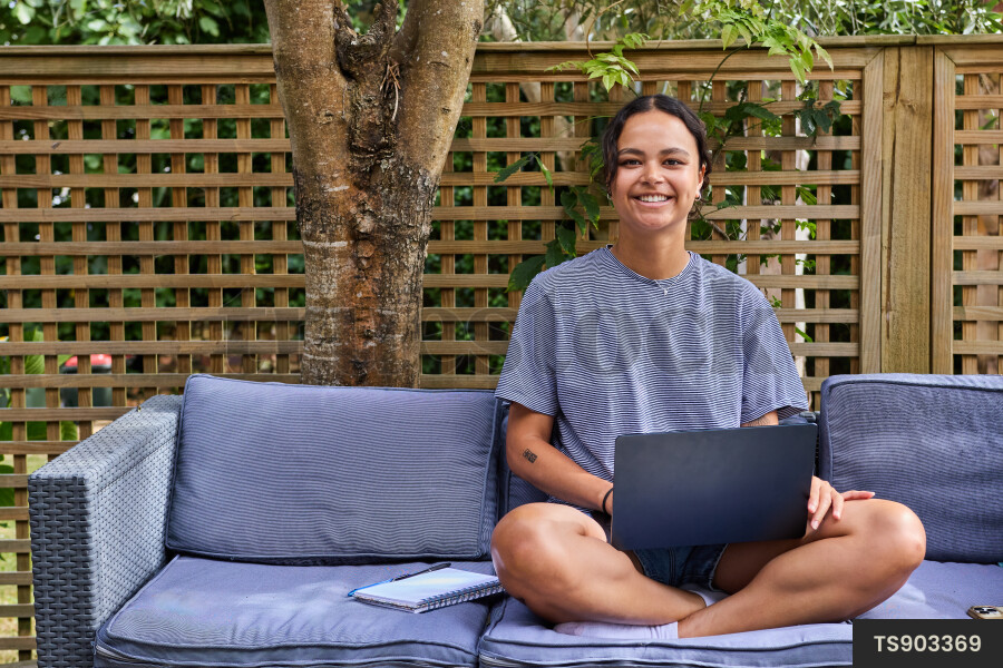 Young woman with laptop sitting on outdoor chair