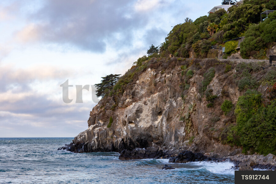 Rocky cliff on coastline under clouds