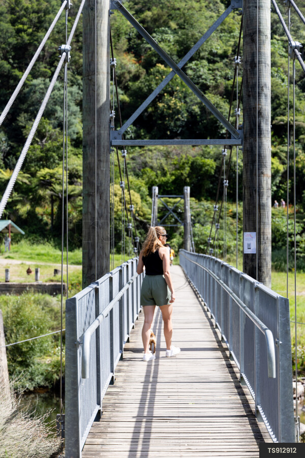 Woman walking dog on bridge