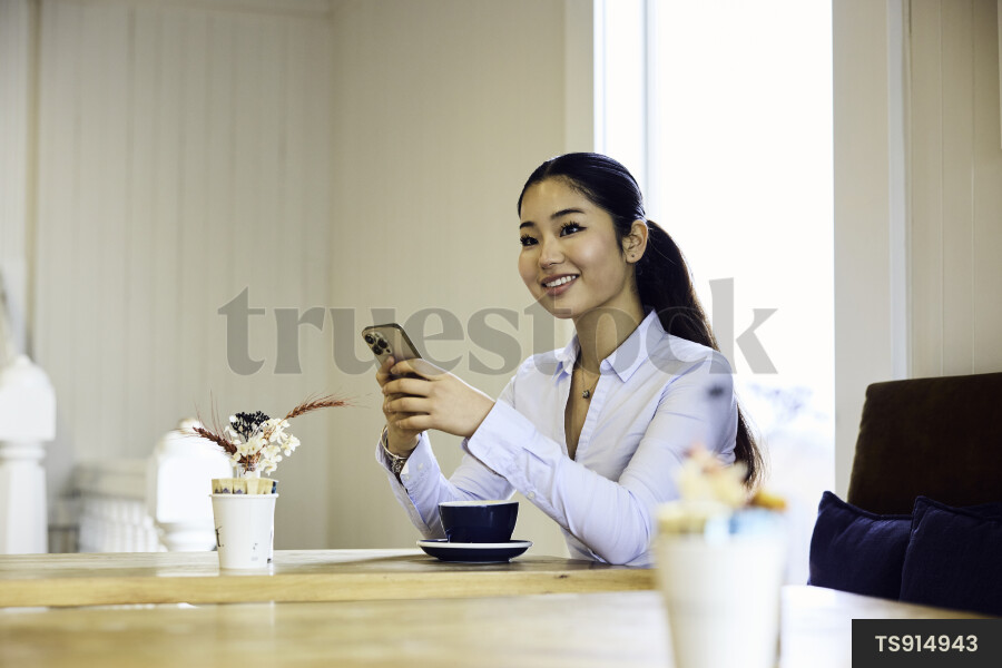 Woman working remotely with smartphone in cafe