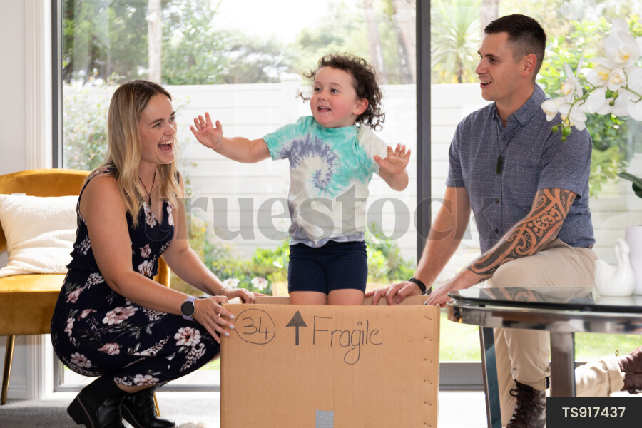Girl playing in cardboard box with parents