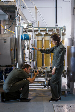 Workers Checking Machinery in Brewery