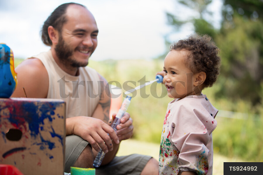 Father and daughter playing with bubbles in garden