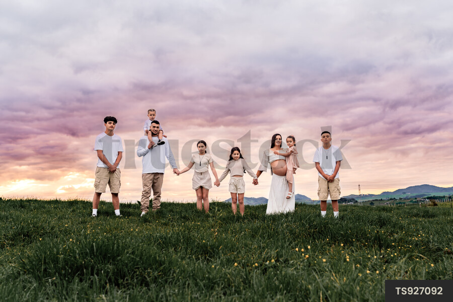 Family holding hands in countryside during sunset