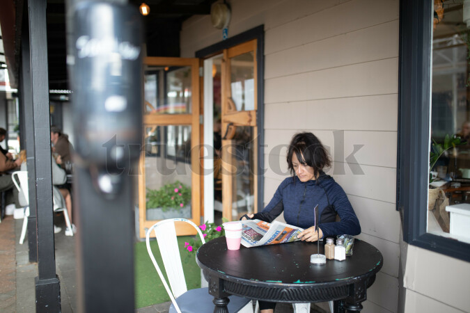 Woman Reading Newspaper at Cafe