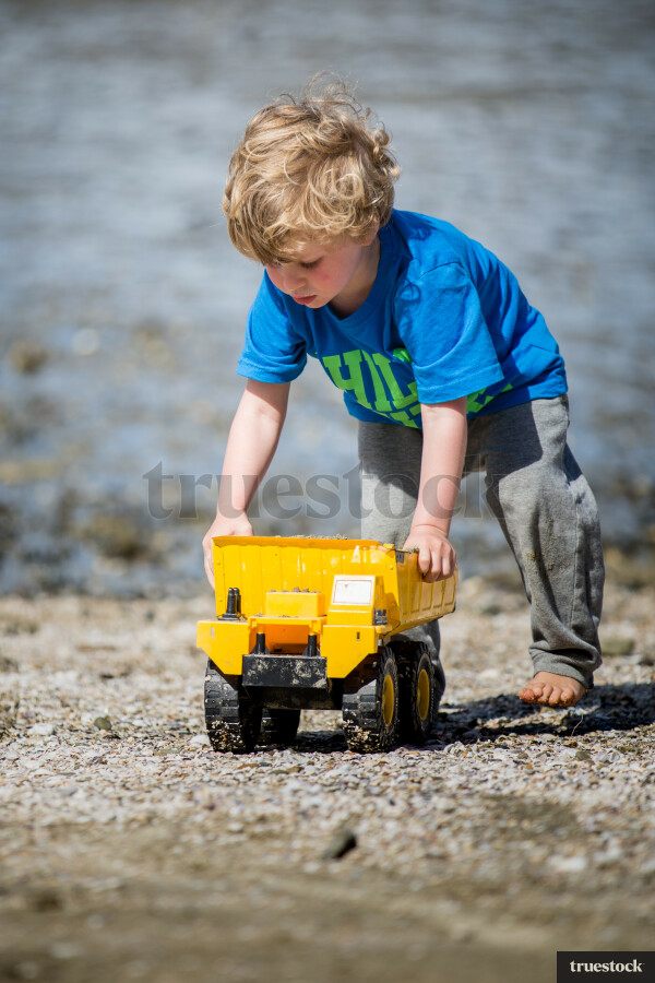 Child playing with toy truck at the beach