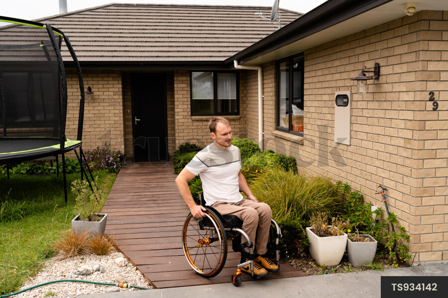 Man in wheelchair by house
