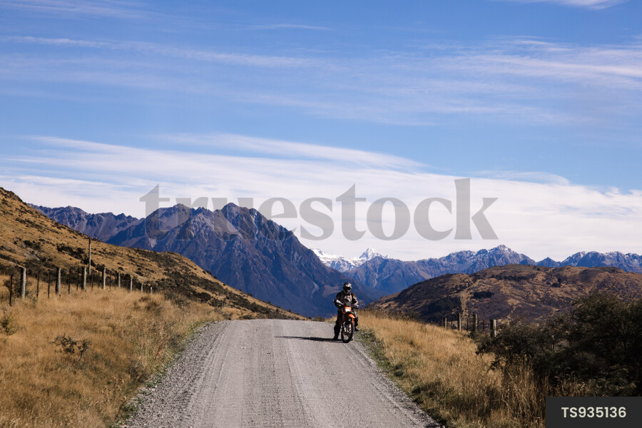 Man on motorcycle on dirt road in Southern Alps