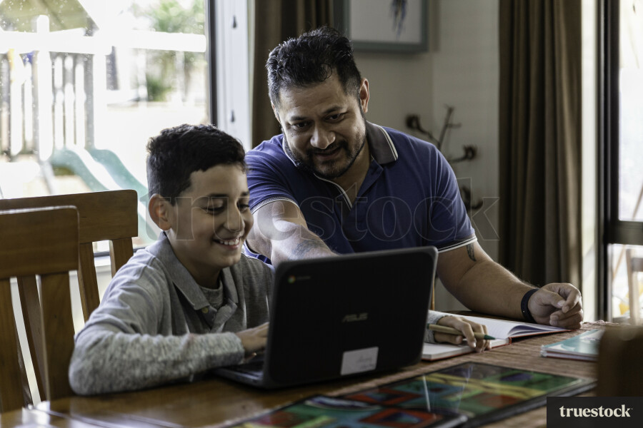 Father and Son using Laptop at Table