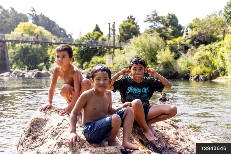 Boys sitting on rock by river